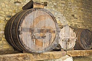 Old wooden vine barrels in an old italian cellar with stone floor and walls
