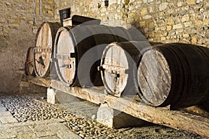 Old wooden vine barrels in an old italian cellar with stone floor and walls