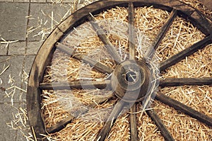 Old wooden wagon wheel lies in the manger