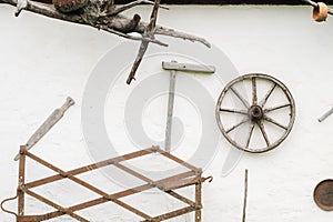 An old wooden wall of a house in the village and ancient cart wheels, tools, etc