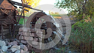 Old wooden water mill with rotating wheel