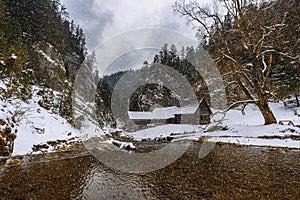 Old wooden water mill in winter with snow falling