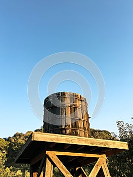 Old wooden water tower on a blue sky.