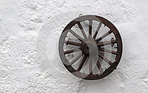 Old wooden wheel on a white stone wall background.Retro style concept for interior design.