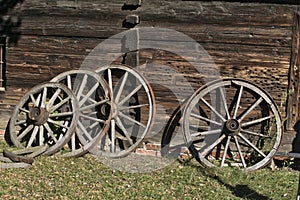 Old wooden wheels for wagon with metal rings near a wooden hut