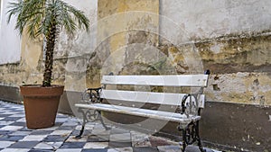 An old wooden white bench with openwork curved metal legs