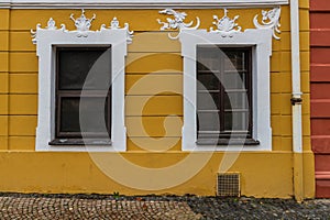 Old wooden white windows in old yellow building in Prague