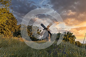 Old wooden windmill at dramatic sunset, historic outdoor background