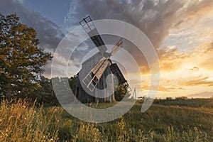 Old wooden windmill at dramatic sunset, historic outdoor background