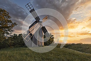 Old wooden windmill at dramatic sunset, historic outdoor background