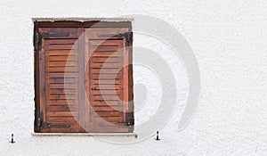 Old wooden window with brown shutters, on rough surfaced wall. photo
