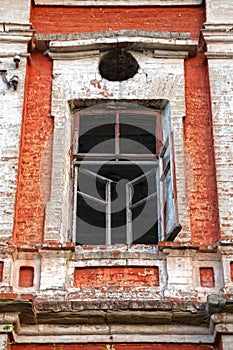 Old wooden window without glass in the brick wall of the facade of an abandoned building