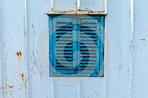 Old wooden window painted blue with rusty lock. Texture, wall of an old wooden house with shuttered windows, painted blue.