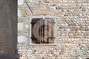 Old wooden window with shutters on a stone wall, Italy.