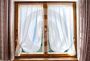 Old wooden window with white curtains