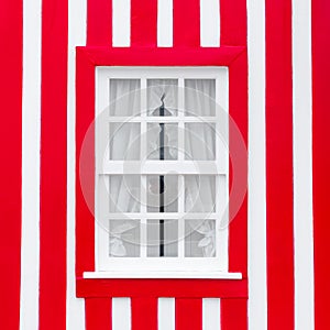 Old wooden window with white frame on the background of the striped red and white wall. Portugal Windows. The exterior