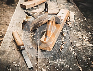 Old woodworking hand tool: wooden plane, chisel and drawing knife in a carpentry workshop on dirty rustic table covered photo