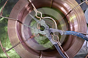 old working strong steel pliers for working on metal in the shop of the plant lie on a coil of copper wire of a large