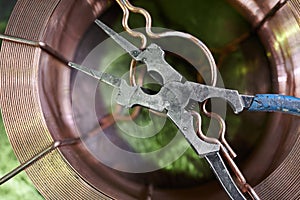 old working strong steel pliers for working on metal in the shop of the plant lie on a coil of copper wire of a large