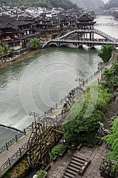 Old World charm along the promenade of Fenghuang Ancient City is highlighted by waterwheels and the towering Nanhua Bridge