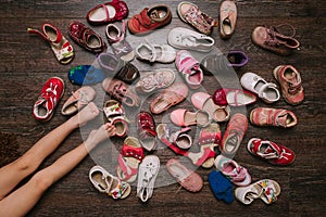 Old worn baby (child, kid) shoes on the floor. sandals, boots, s