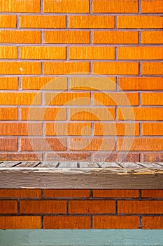 Old worn bench on a brick wall