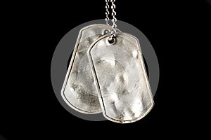 Old and worn blank military dog tags isolated black