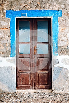 Old worn brown wooden windowed door of a vintage stone house