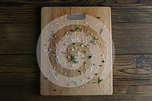 Old worn, cracked and scratched wooden cutting board. sprinkled with spices. Top views with clear space