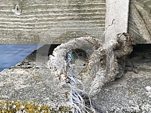 Old worn frayed knot tied to a bridge