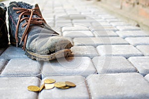 Old worn leather boot in dark blue with colorful brown laces. Poverty concept. Old and torn shoes and thrown to the ground coins.