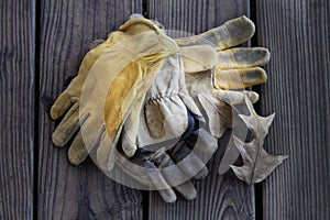 Old, worn, leather work gloves on wooden background