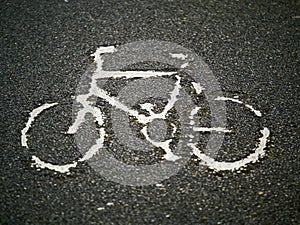 Old worn out bicycle sign on asphalt road
