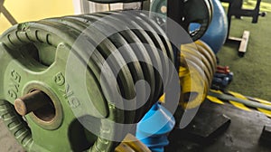 Old, worn out color-coded rubberized grip plates on a horizontal weight plate stand or rack at a gym or fitness center