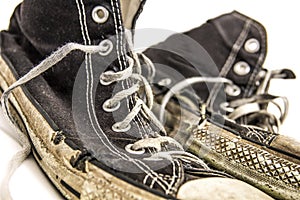 Old worn out pair of black and white high top tennis shoes on white background