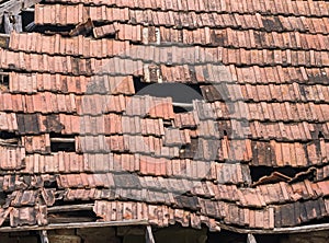 Old worn out red brick roof with missing tiles