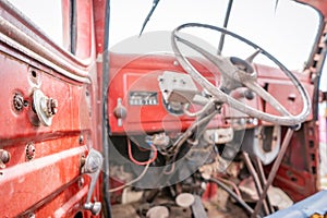 Old worn out, rustic red tractor interior with broken parts and exposed driver area