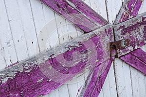 Old and worn out white and purple wooden door with rusted lock