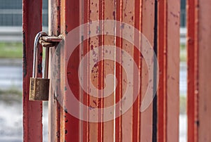 Old worn padlock locked on the paint-shabby gate.