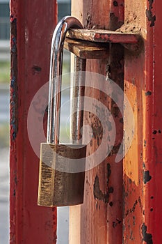 Old worn padlock locked on the paint-shabby gate.