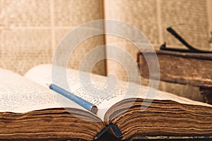 Old worn shabby jewish books in leather binding and open blurred Torah in the background. Closeup. Selective focus