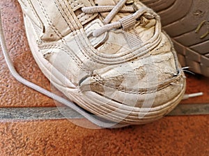Old worn sneakers torn on the tiled floor