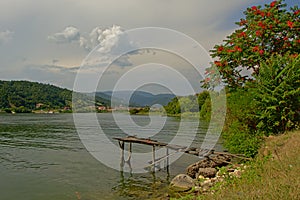 Old worn woon scaffolding along Danube river with shrubs and mountains in the background