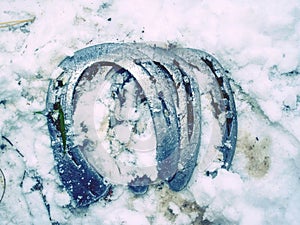 Old wornout rusted horseshoe lying on snow