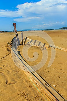 Old wreck fishing boat buried in the sand with blue sky on cloud