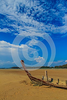Old wreck fishing boat buried in the sand with blue sky on cloud