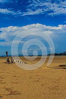 Old wreck fishing boat buried in the sand with blue sky on cloud