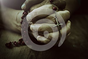 Old wrinkled woman hands holding a rosary. Closeup of christian  woman hands holding rosary while praying God