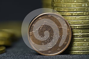 An old, 2009 year, two euro cent coin put on edge in front of piles of coins