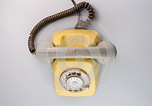 Old yellow antique rotary telephone on blue background. Vintage landline phone with dial, twisted cable and grey